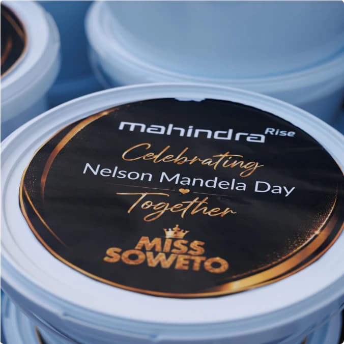 Close-up of a Mandela Day donation bucket lid branded with Mahindra Rise and Miss Soweto