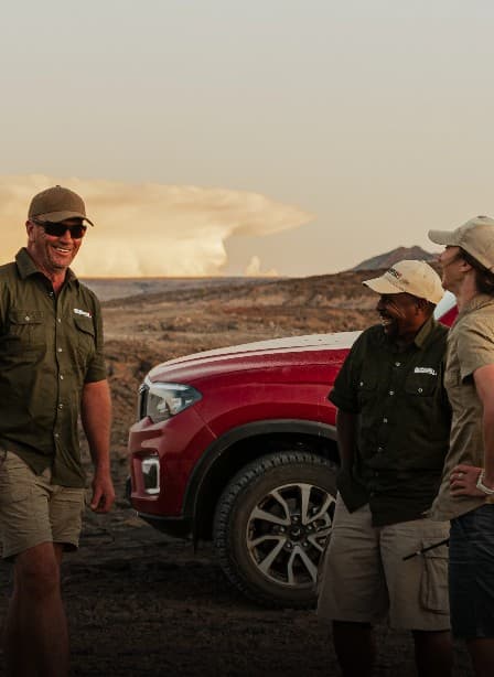 Team Mahindra expedition member smiling beside a red Scorpio-N