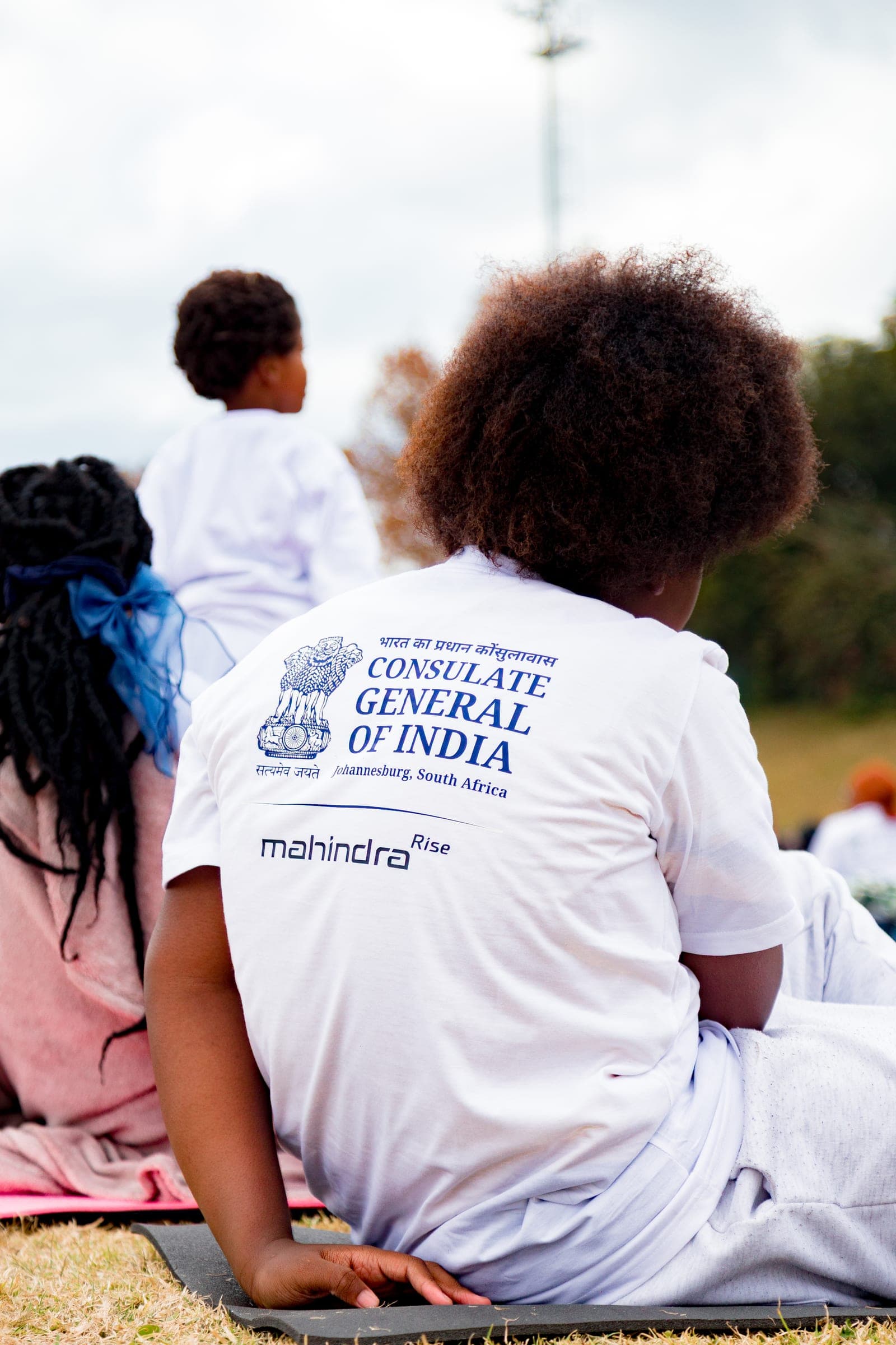 Back of a white event t-shirt with Consulate General of India and Mahindra Rise logos