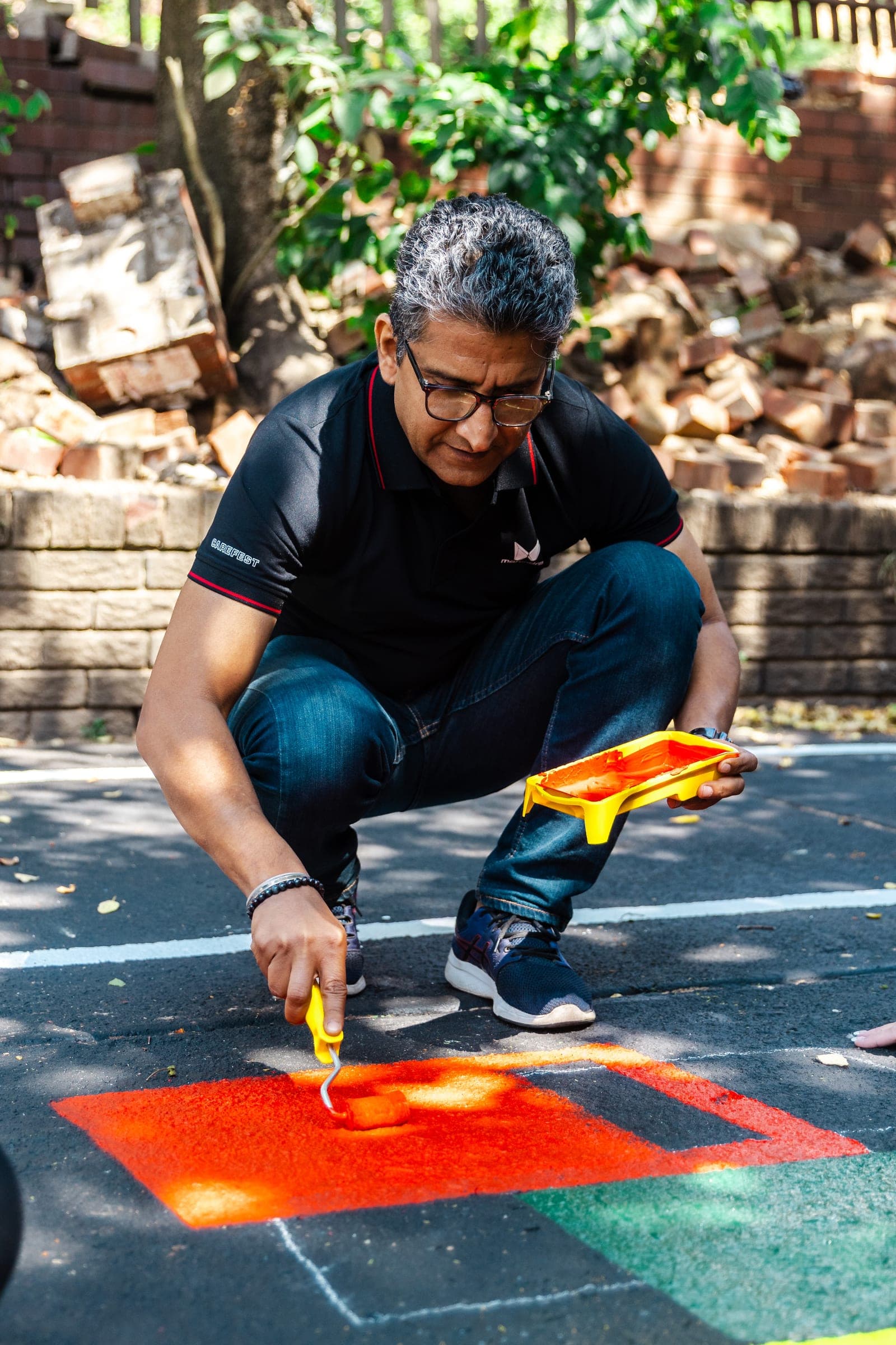 Volunteer painting bright orange road markings on the ground