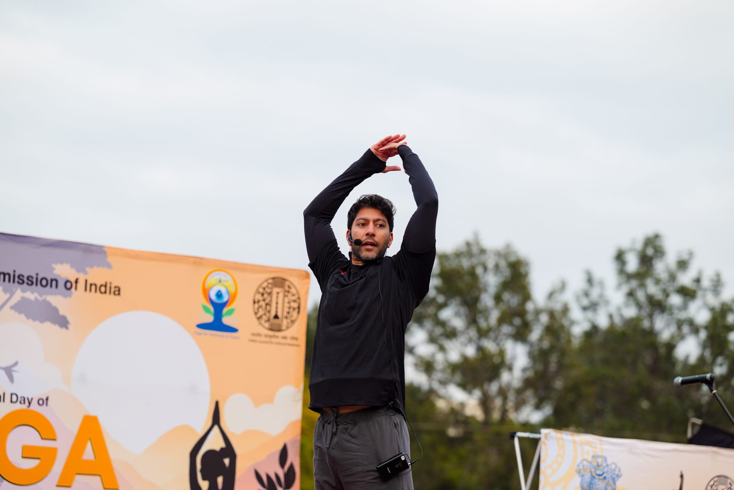 Instructor stretching with arms overhead on the outdoor Yoga Day stage