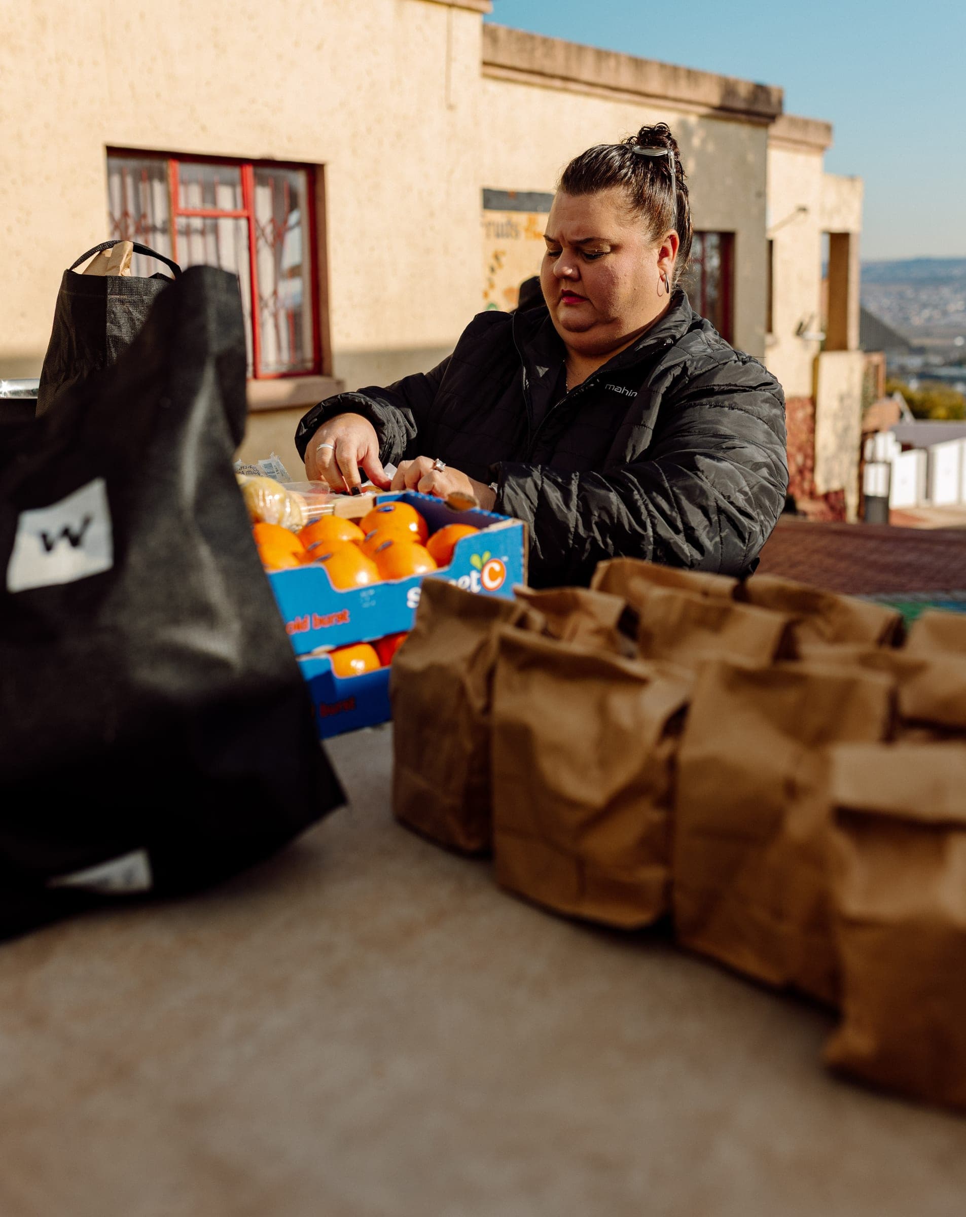 Volunteer packing oranges and food parcels for the Ba-Tliseng community visit