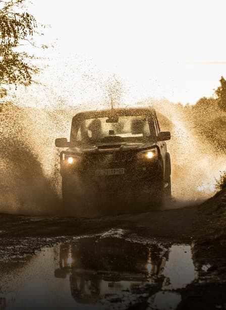 Mahindra Pik Up splashing through a muddy off-road course